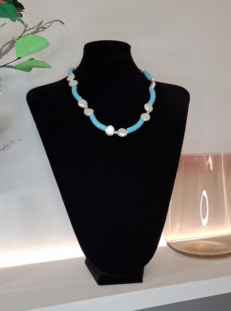 Collana statement artigianale con pietre turchesi geometriche e elementi in madreperla bianca, design essenziale e luminoso.