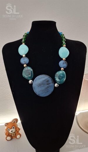 Collana artigianale con pietre ovali azzurre, tonalità blu e verdi e pendente centrale, design equilibrato e ispirazione marina.