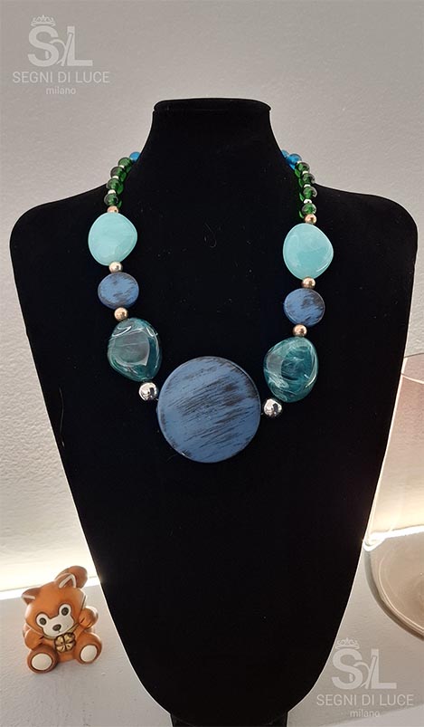 Collana artigianale con pietre ovali azzurre, tonalità blu e verdi e pendente centrale, design equilibrato e ispirazione marina.