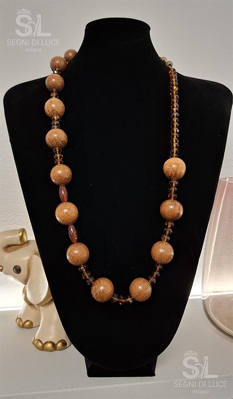 Collana artigianale con elementi in legno e resina e perline sfaccettate, design boho-chic caldo e naturale.