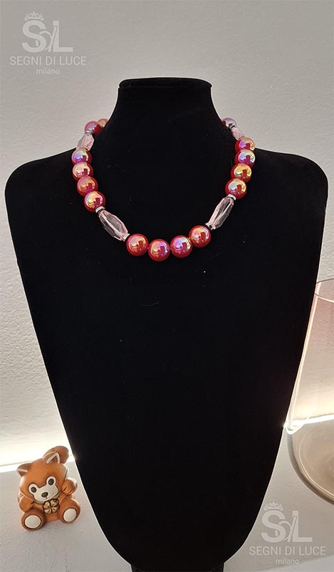 Collana artigianale con perle rosse marmorizzate in oro e segmenti trasparenti rosati, design luminoso e dinamico.