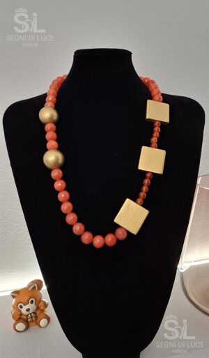 Collana statement artigianale con perle arancio marmorizzate e struttura geometrica dorata, design scultoreo e vibrante.