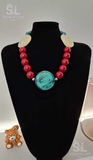 Collana artigianale da 50 cm con pietra centrale verde acqua sfaccettata, perle rosse rotonde e dischi madreperlati bianchi.